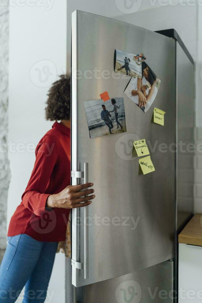 hambriento mujer en pie en cocina, buscando su refrigerador foto