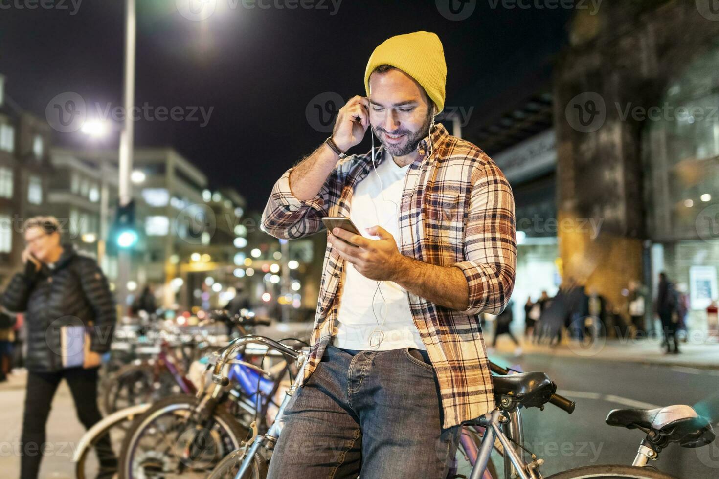 UK, London, man commuting at night in the city and looking at his phone photo