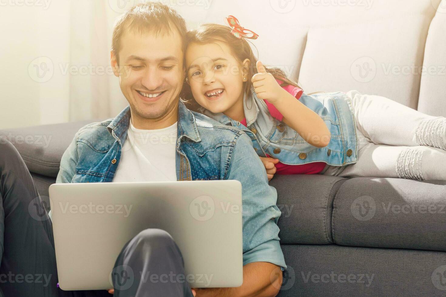 Bearded man and little girl at home family time sitting on floor on carpet browsing laptop together smiling joyful photo