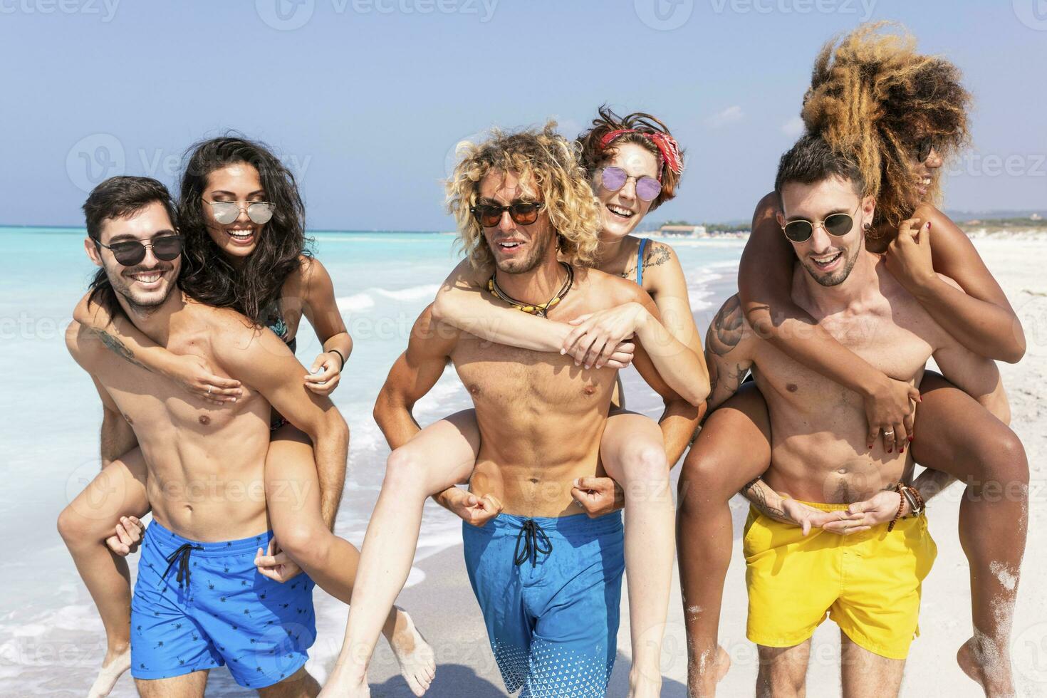 Friends walking on the beach, carrying girlfriends piggyback photo