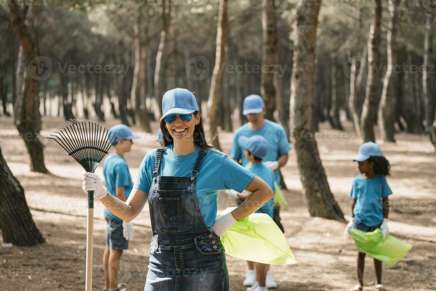Portrait of a smiling woman with group of people collecting garbage in a park photo
