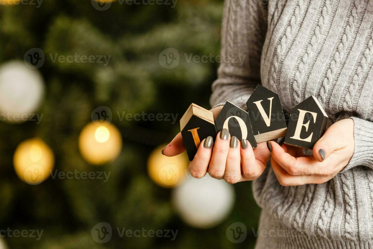 woman holds letters love near christmas tree with toys photo