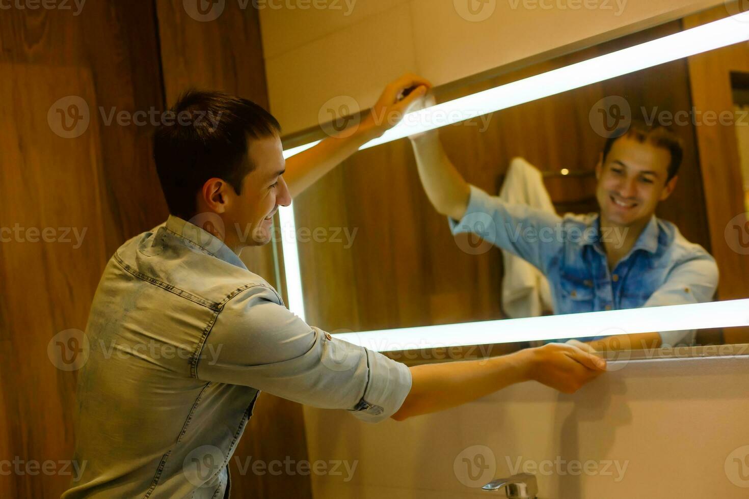 Man installing a mirror on wall in his renewed bathroom photo