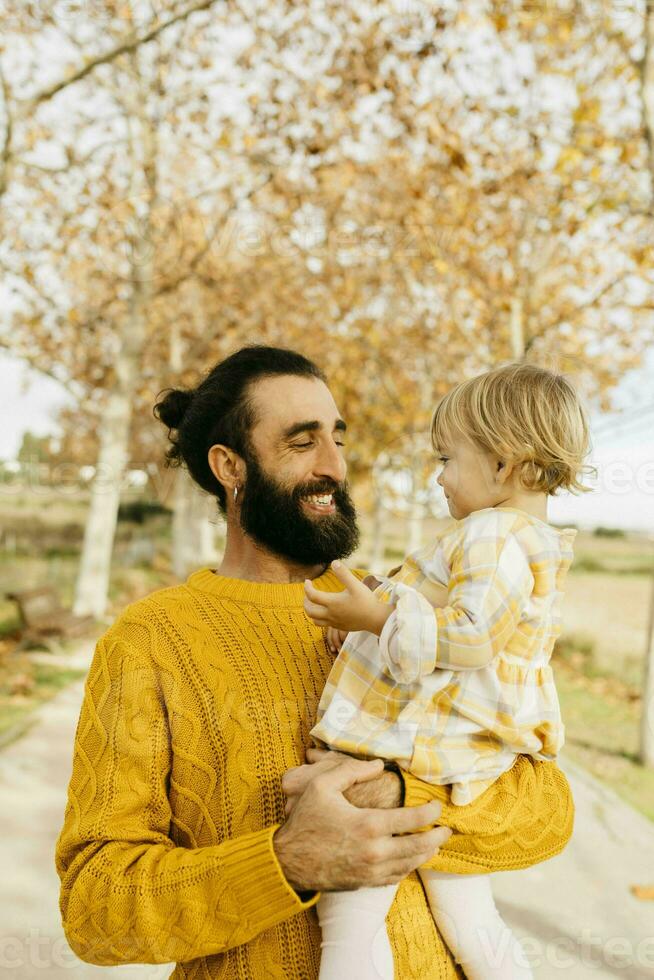 Father carrying his daughter on a morning day in the park in autumn photo