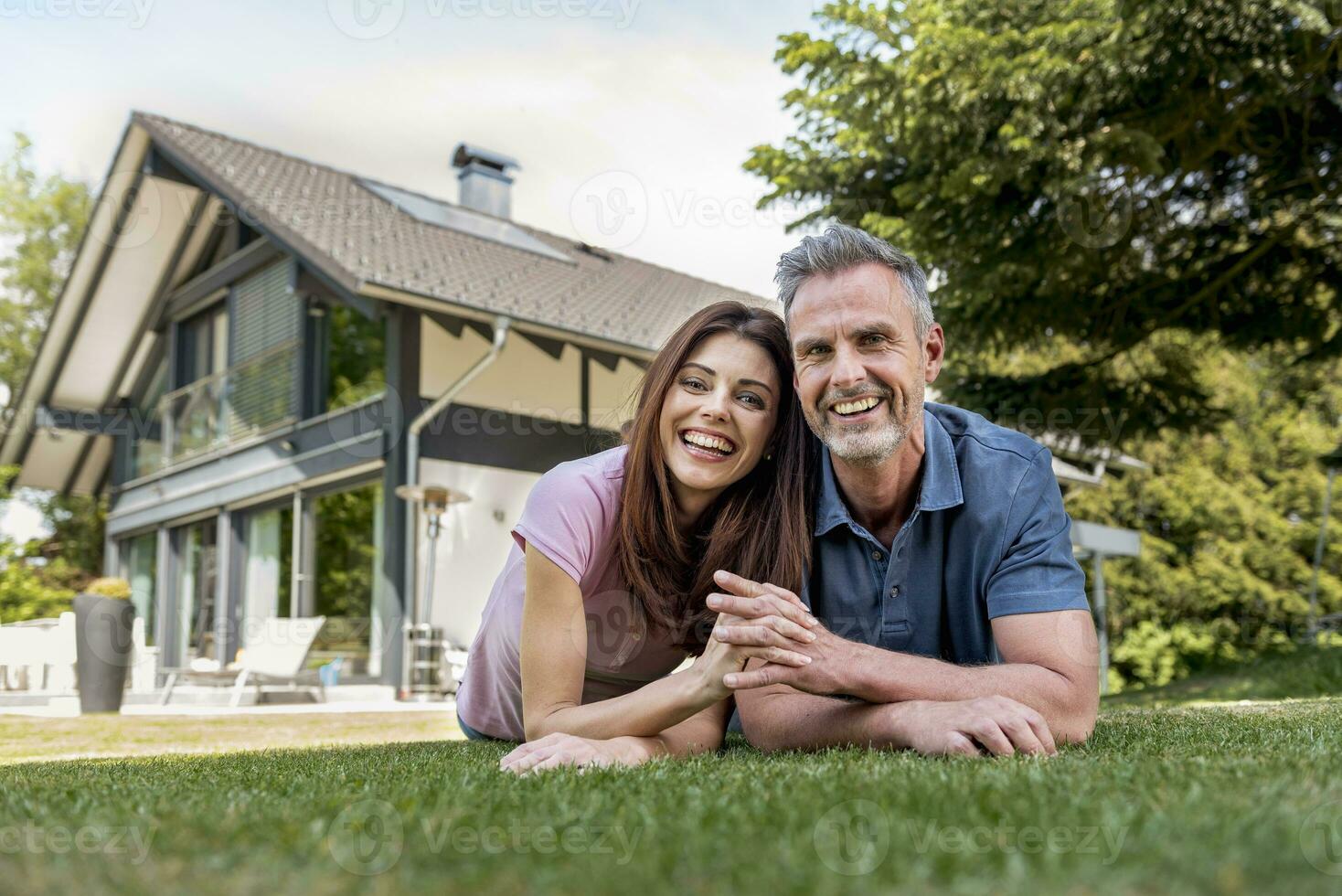 Portrait of happy couple lying in garden of their home photo