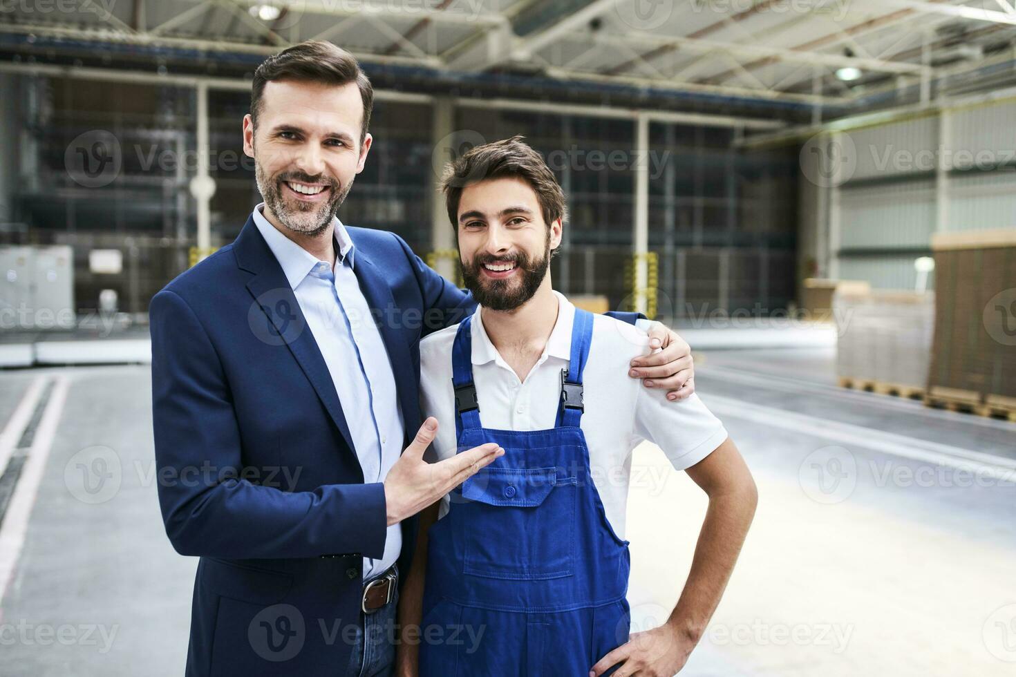 Portrait of happy businessman and worker in a factory photo