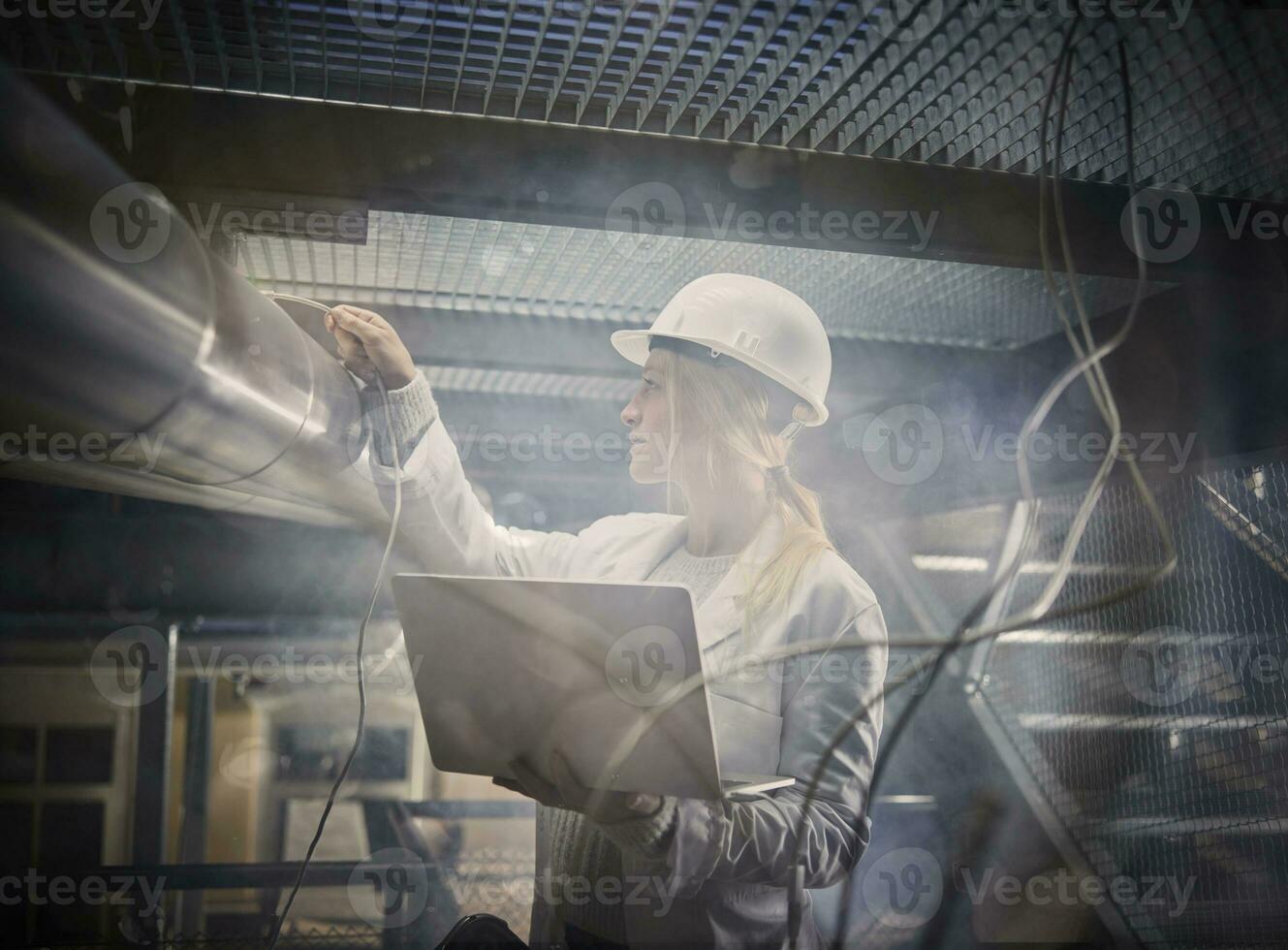 Female technician working on pipeworks, using laptop photo