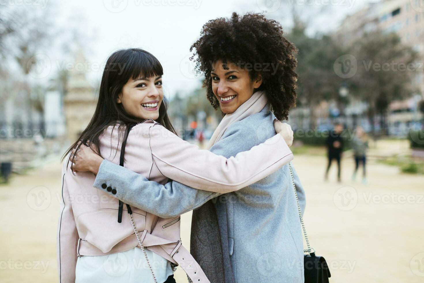 España, Barcelona, retrato de dos contento mujer en ciudad parque abrazando torneado redondo foto