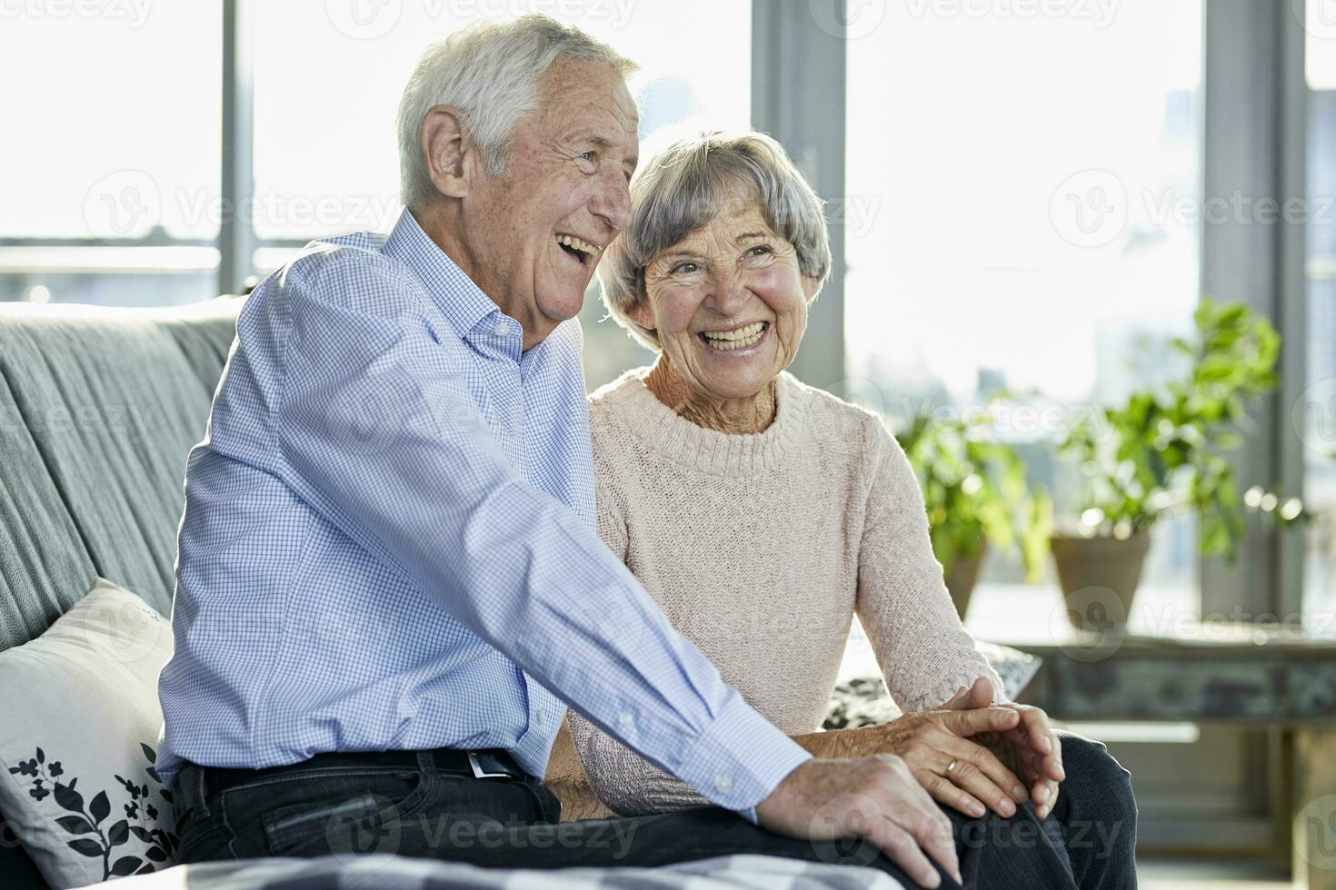 Portrait of laughing senior couple sitting together on couch photo