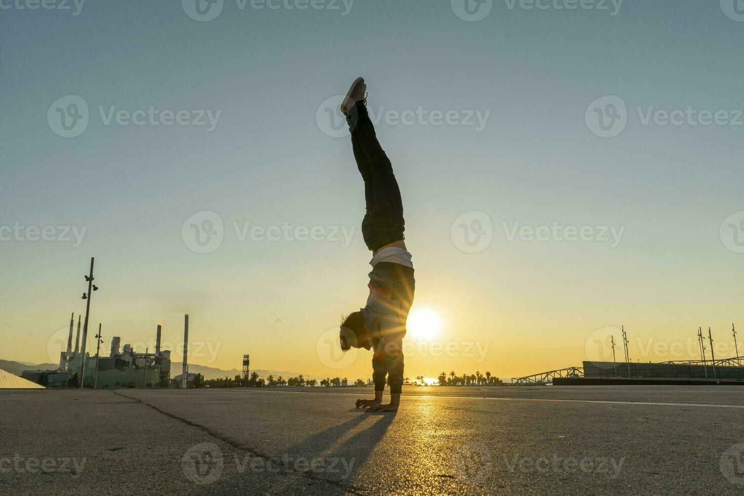 acróbata haciendo parada de manos en el ciudad a amanecer foto