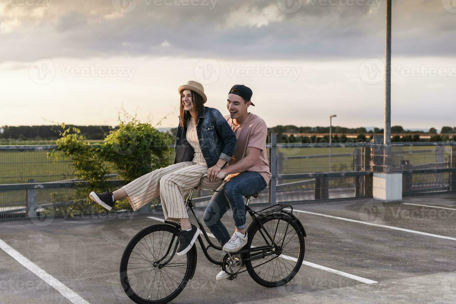 contento joven Pareja juntos en un bicicleta en estacionamiento cubierta foto