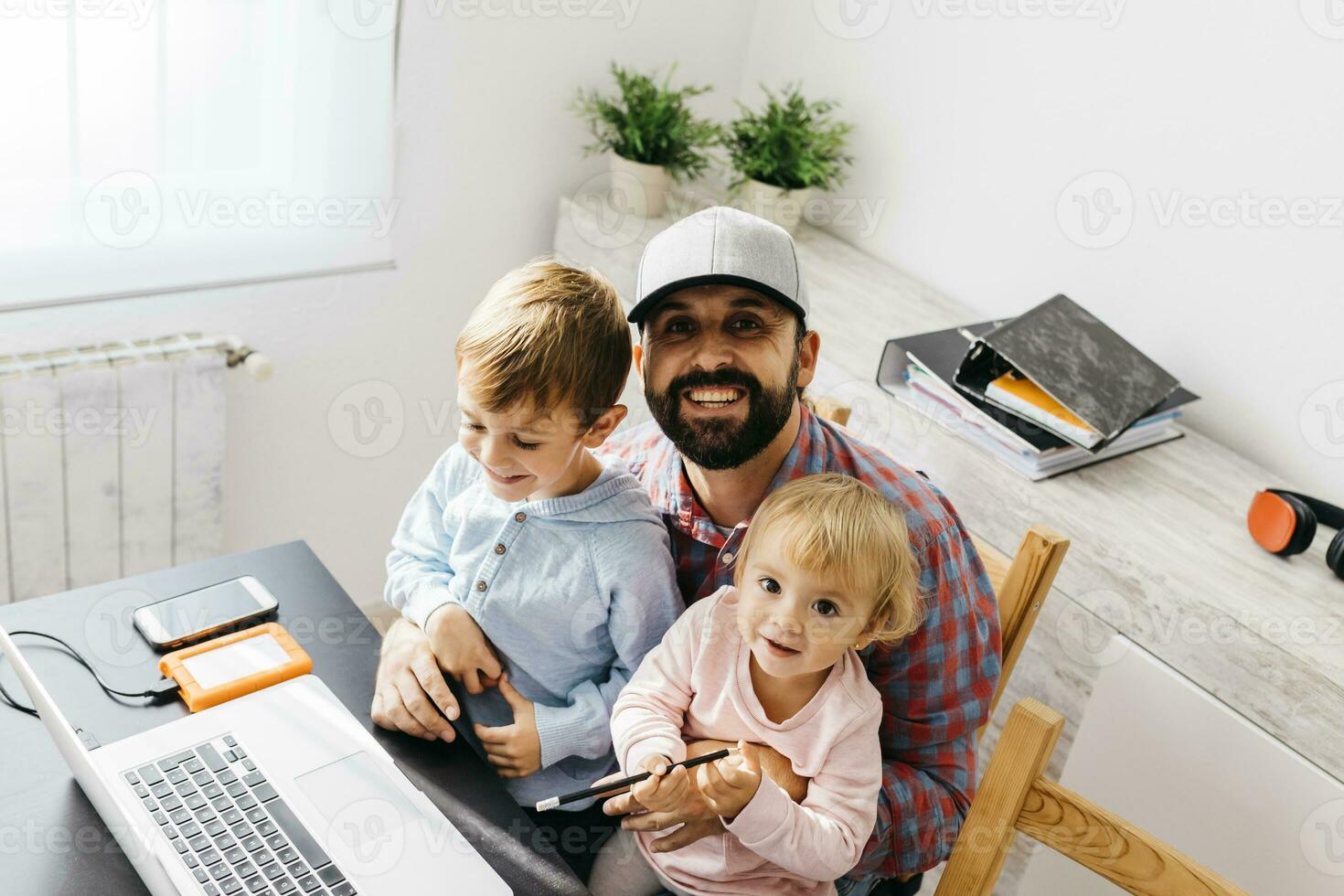 Father working at home, using laptop with his children on his lap photo