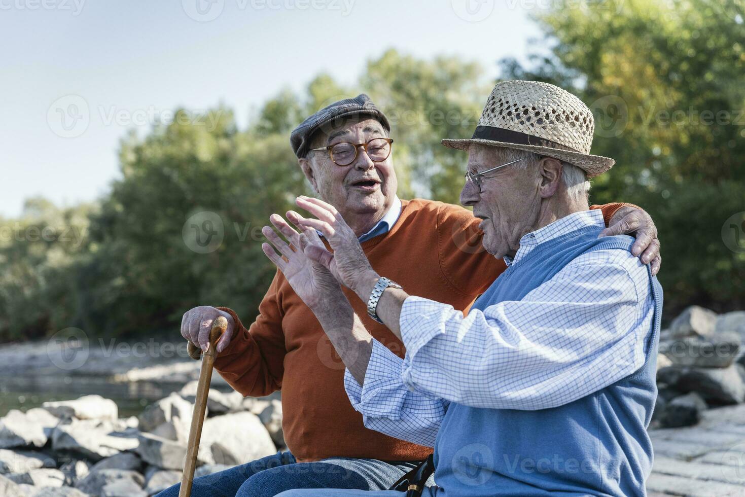 Two old friends sitting by the riverside, having fun photo