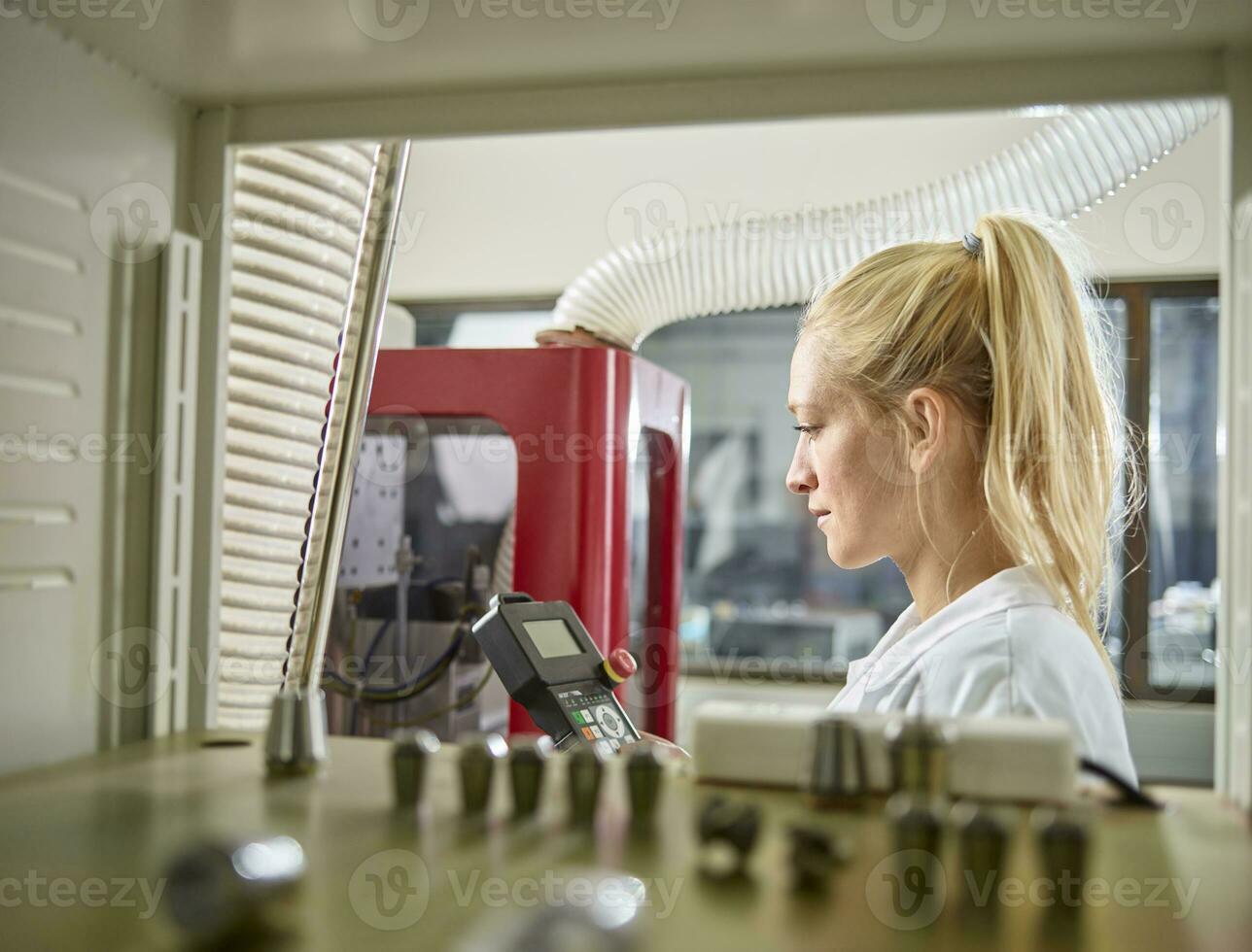 Female technician maintaining CNC machine photo