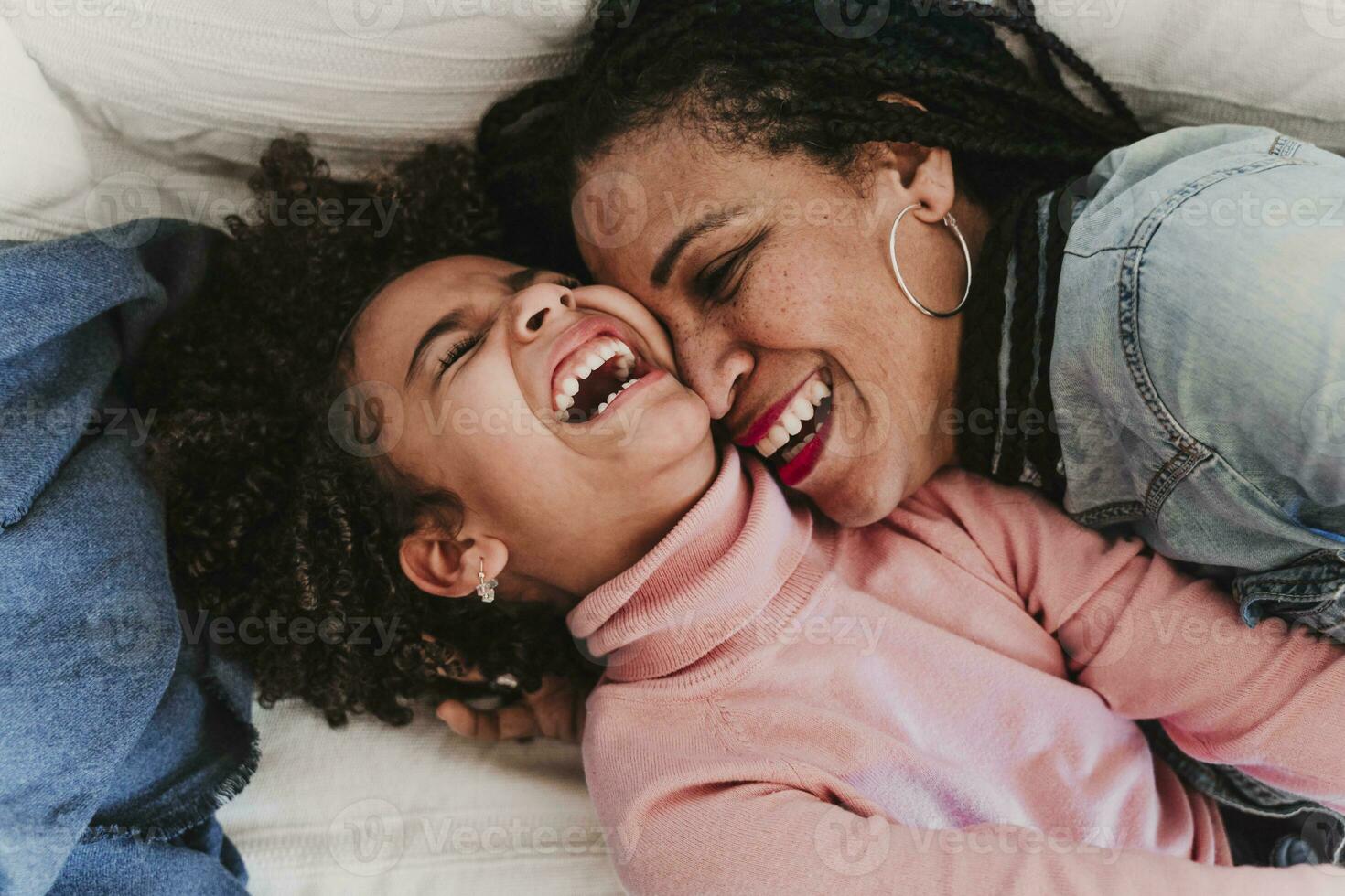 Portrait of laughing little girl and her mother having fun together at home photo
