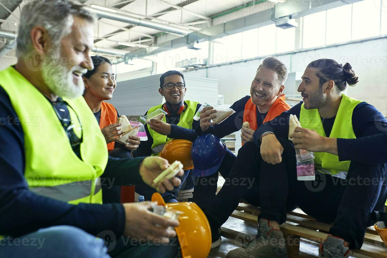 Happy workers in factory having lunch break together photo