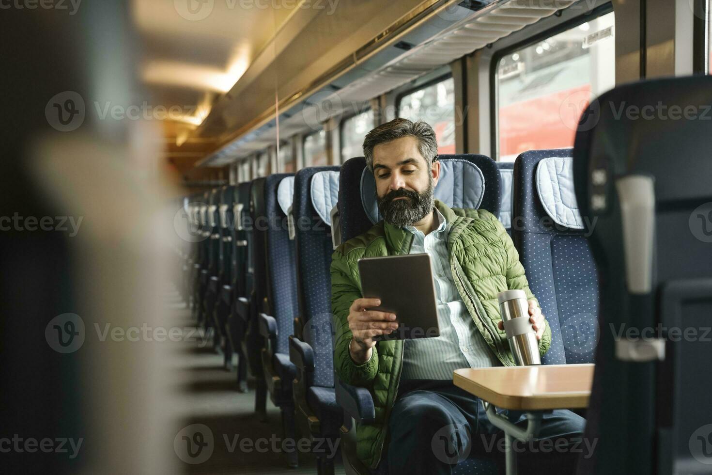 hombre sentado en tren utilizando tableta foto