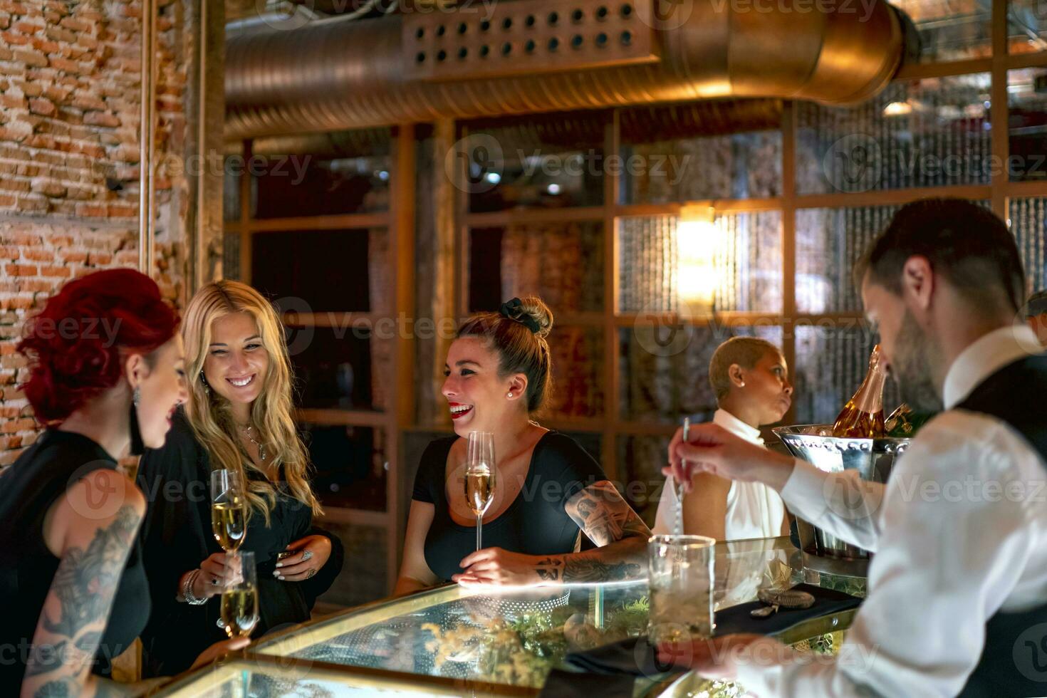 Smiling friends talking while sitting at bar counter in pub photo