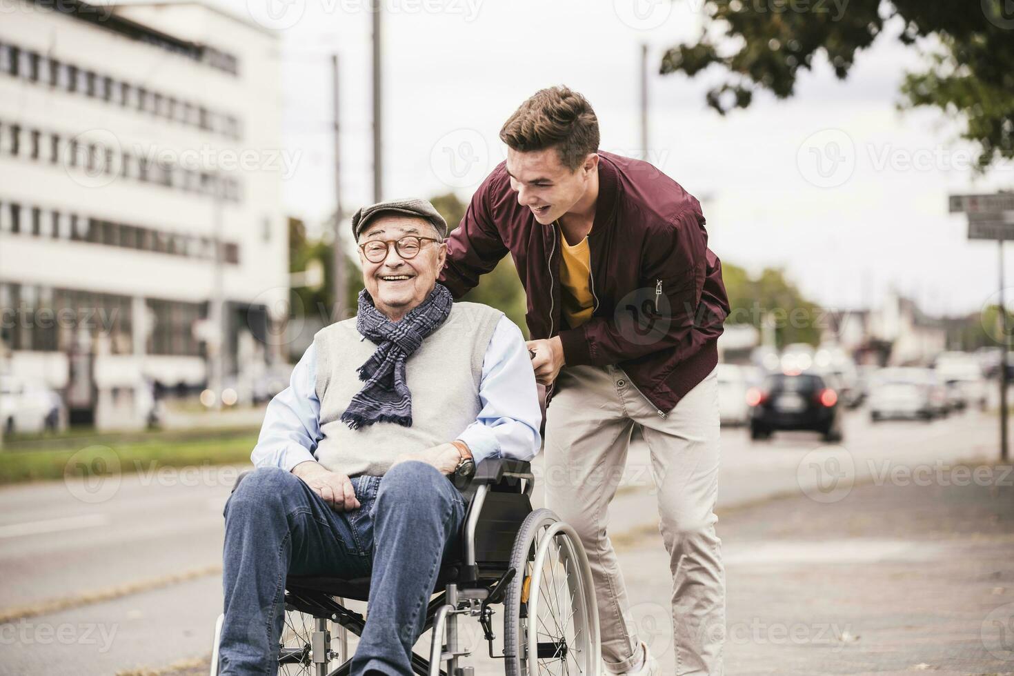 Young man pushing happy senior man in wheelchair photo