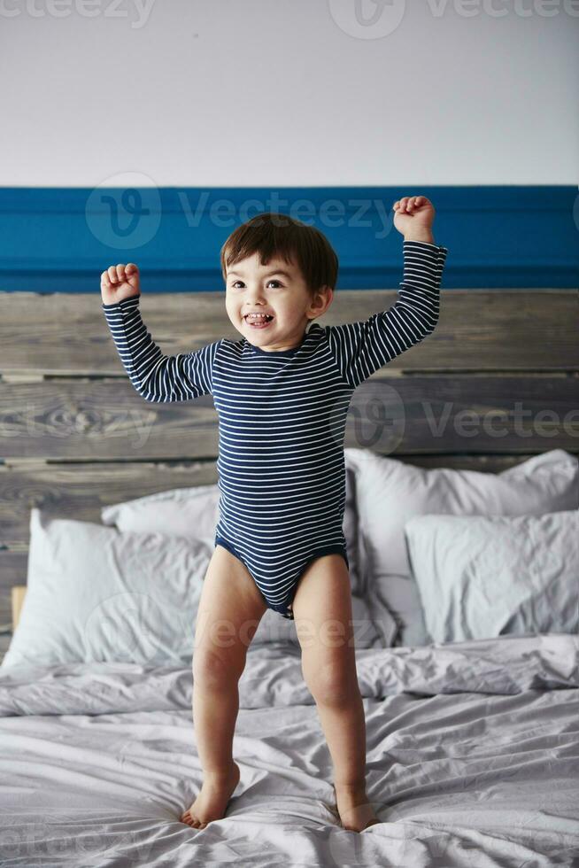Portrait of happy toddler jumping on bed photo