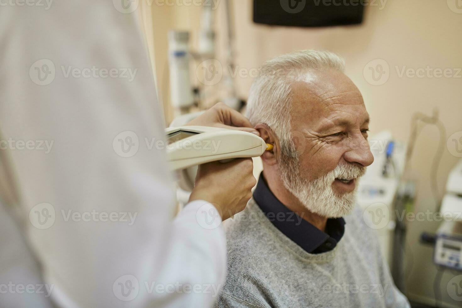 ENT physician examining ear of a senior man photo