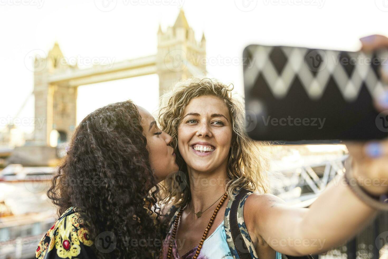 UK, London, two friends taking a selfie with Tower Bridge in background photo