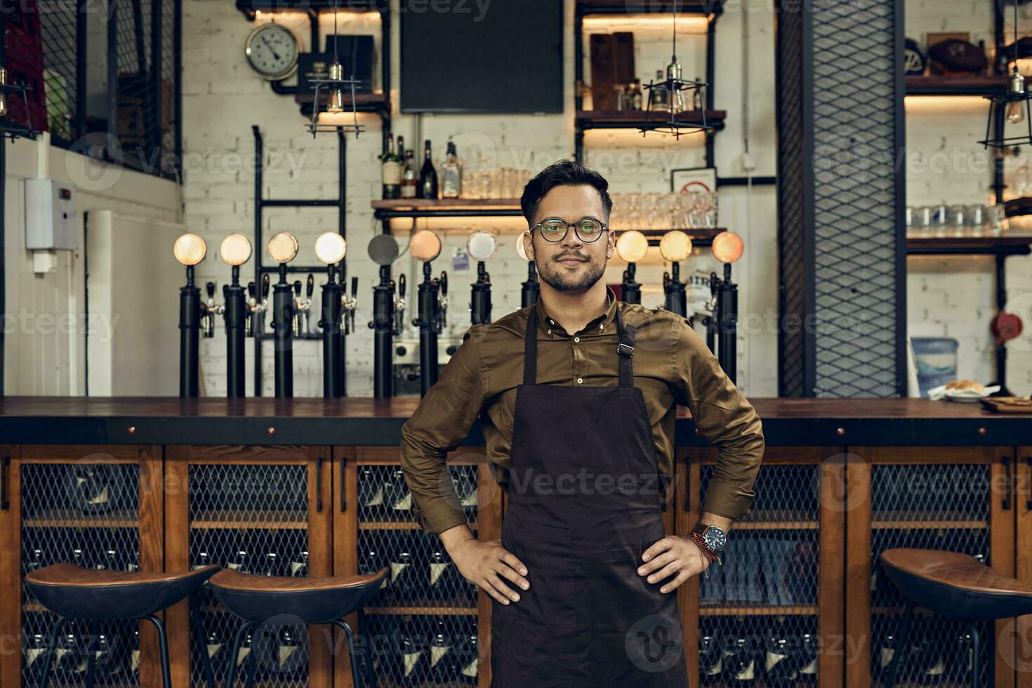 Portrait of a confident waiter at the counter in a pub photo