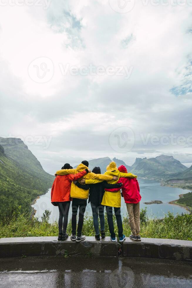 Norway, Senja island, rear view of friends embracing on an observation point at the coast photo