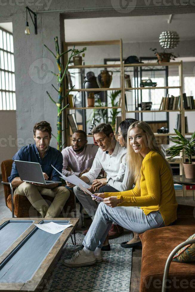 Business team using laptop and discussing documents in loft office photo