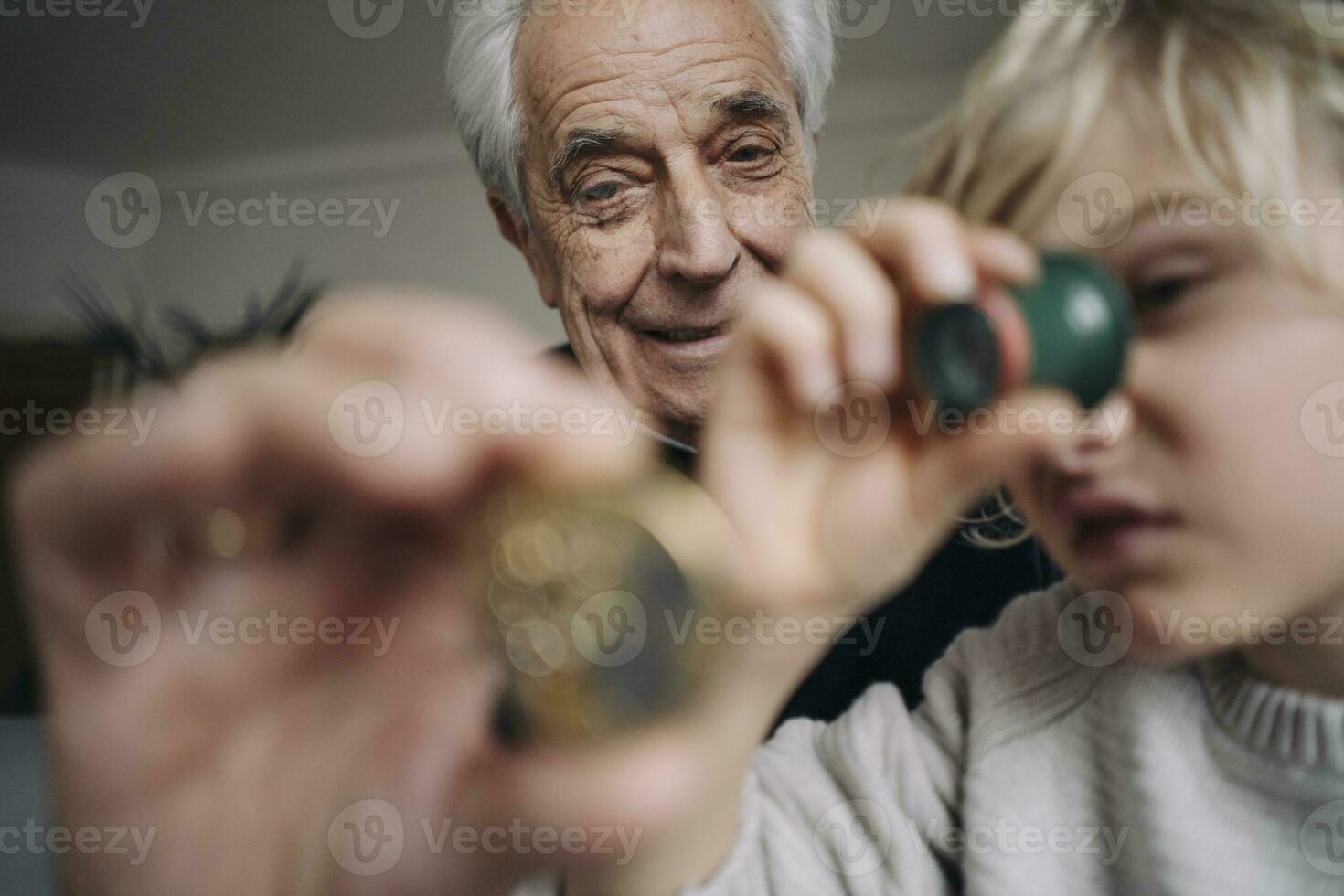 Watchmaker and his grandson examining watch together photo