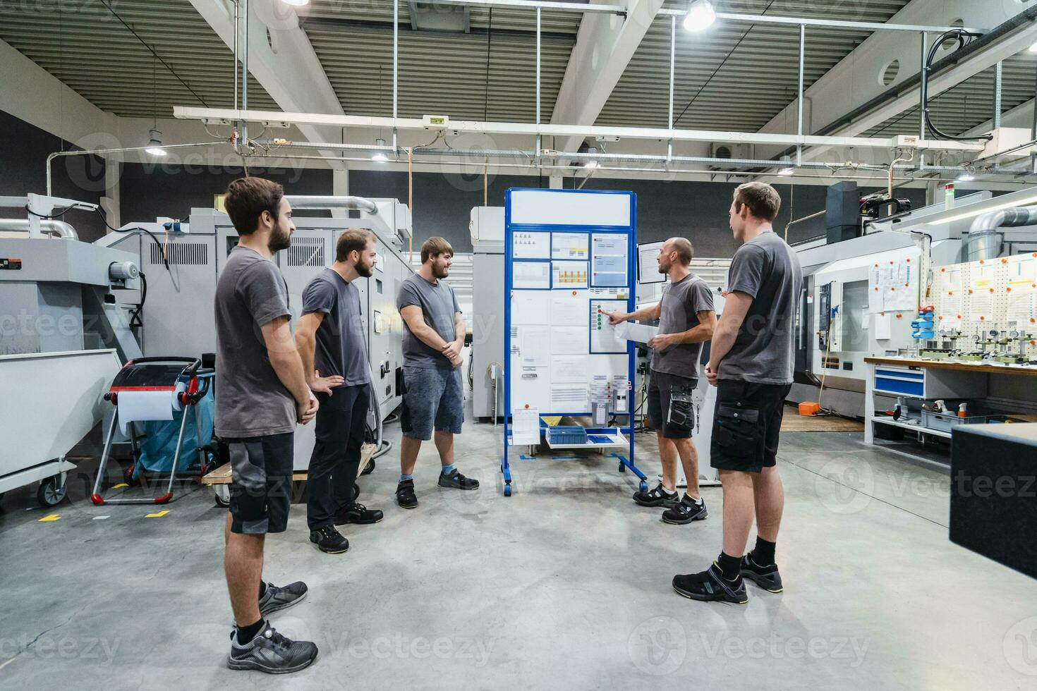 Maintenance engineers planning over chart on whiteboard while standing in meeting at industry photo