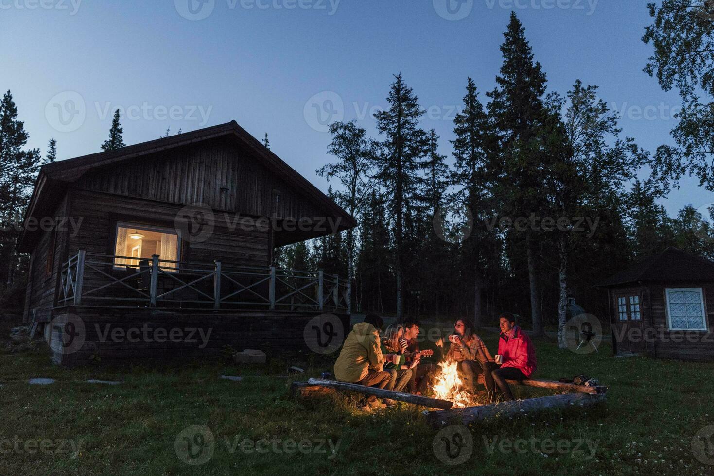 Group of friends sitting at a campfire, talking and drinking tea photo