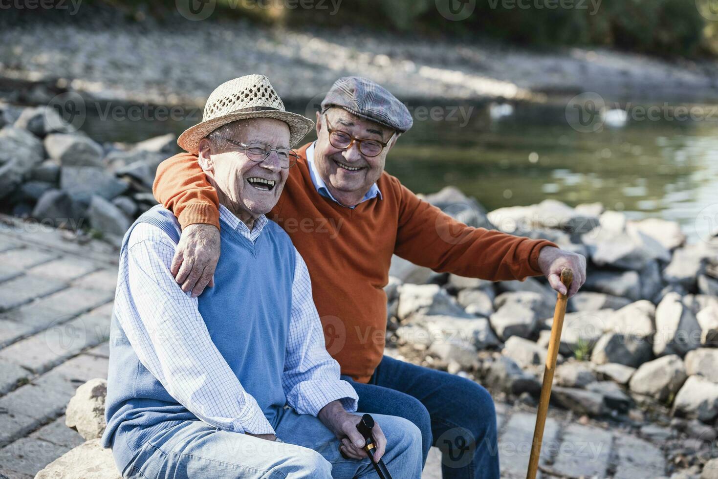Two old friends sitting by the riverside, having fun photo
