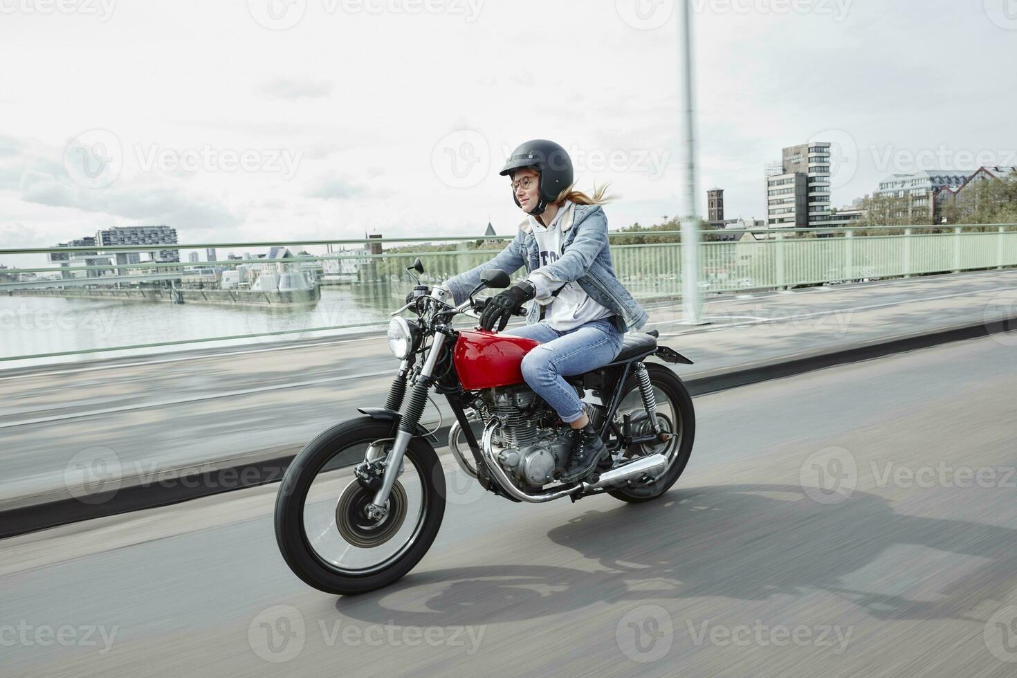 Alemania, Colonia, joven mujer montando motocicleta en puente foto