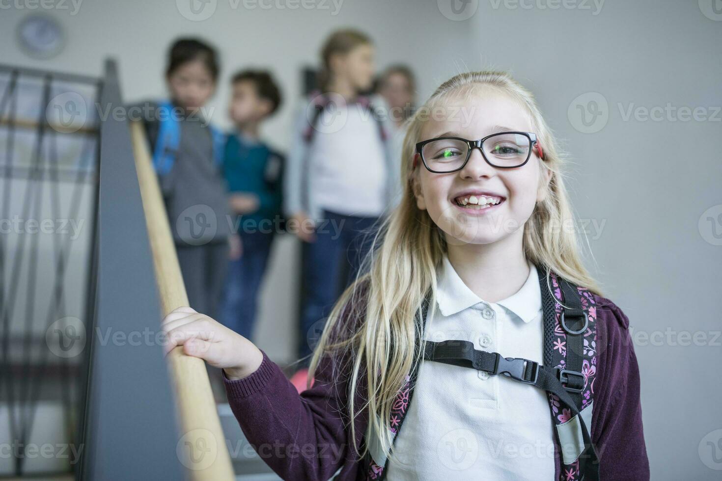 Portrait of happy schoolgirl with classmates on staircase leaving school photo