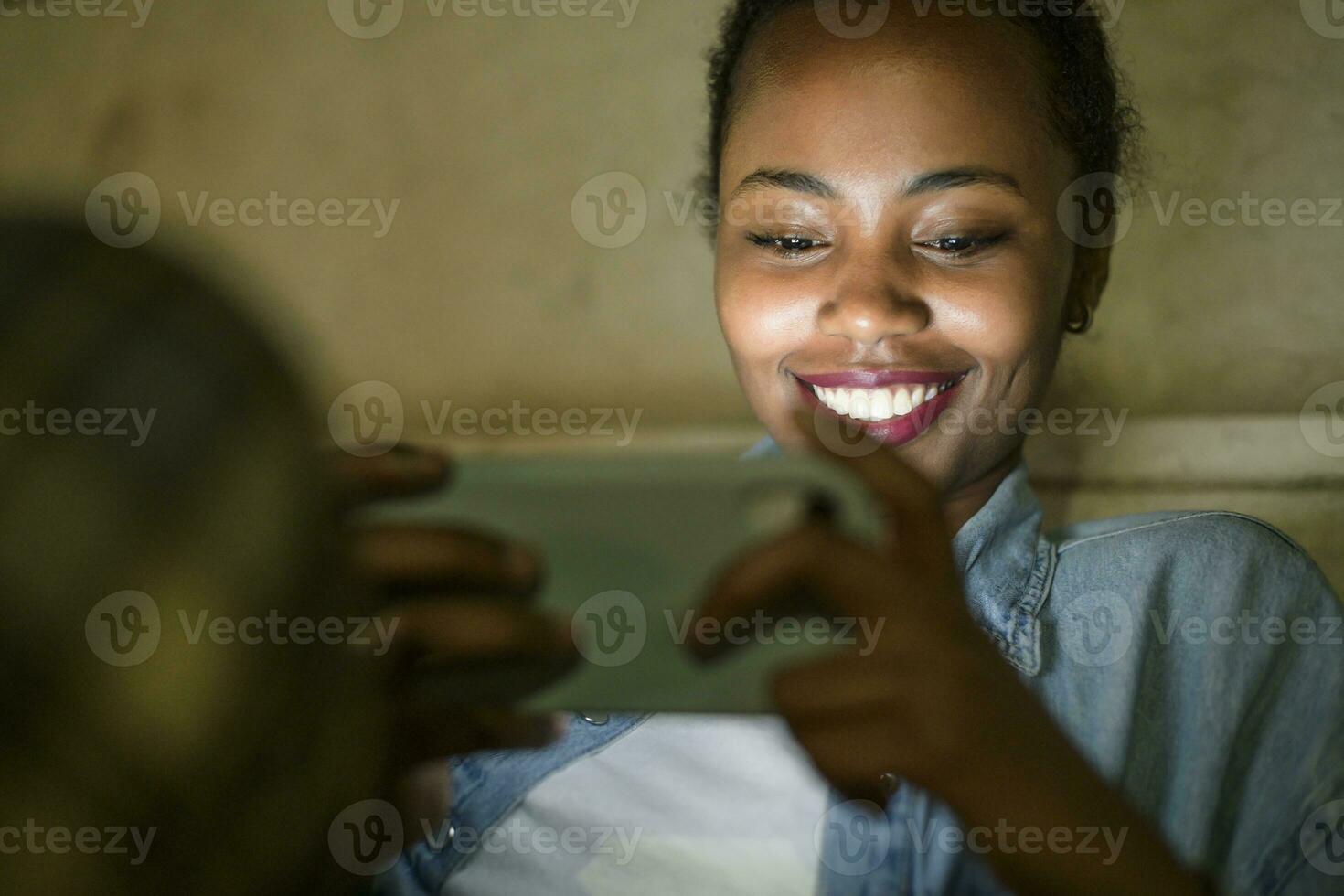 Portrait of happy young woman using smartphone by night, Lisbon, Portugal photo
