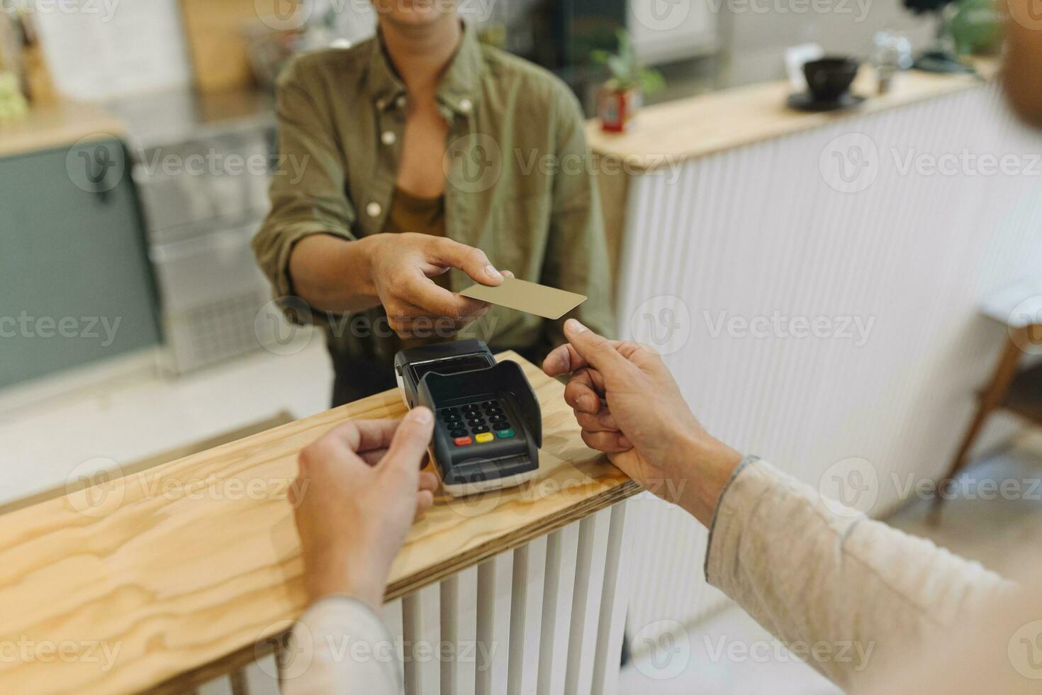 Midsection of female entrepreneur giving credit card to customer at checkout in cafe photo