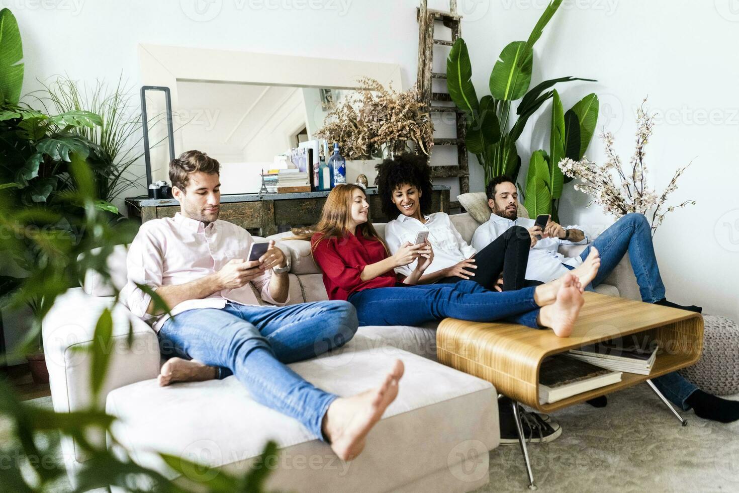 Friends sitting on couch, working casually together, using smartphones photo