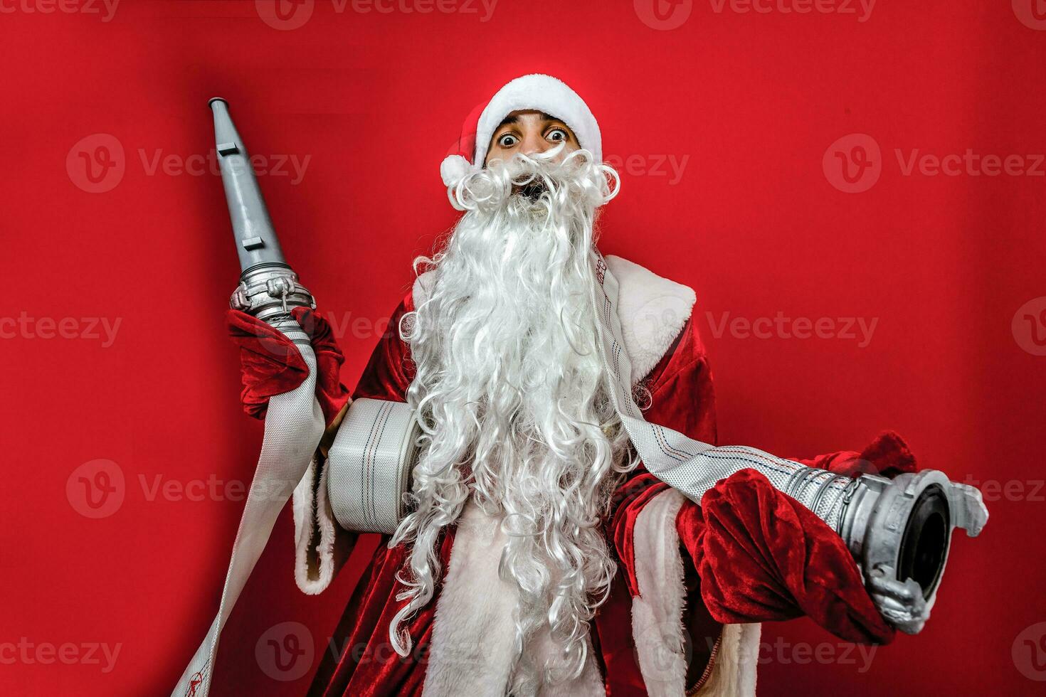 Christmas man in santa clothes with fire Hose standing against isolated white background photo