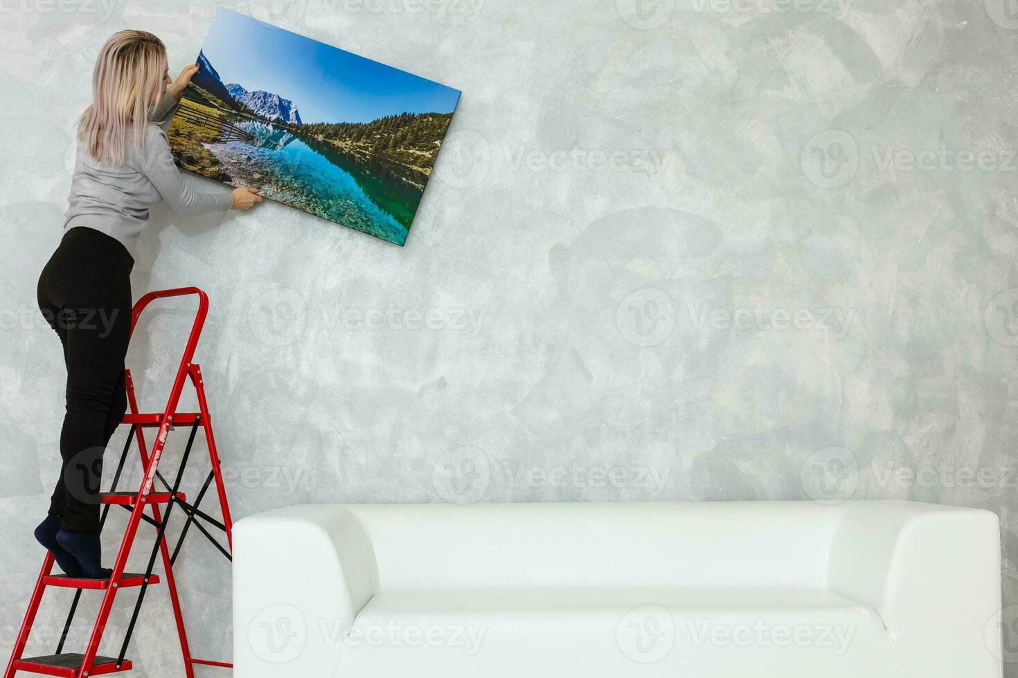 Long-haired girl hanging pictures in frames on wall at house photo