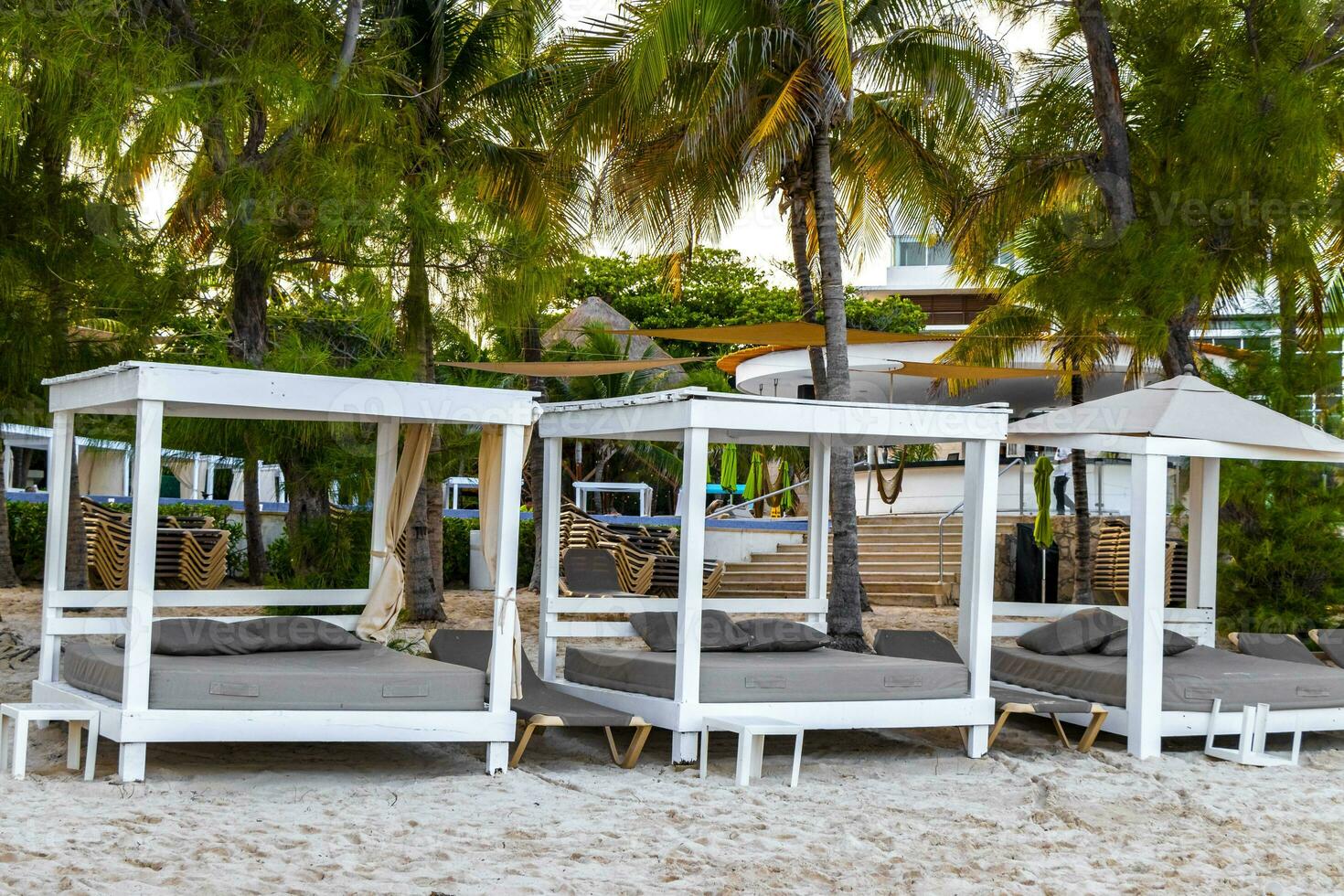 Palapa thatched roofs palms parasols sun loungers beach resort Mexico. photo