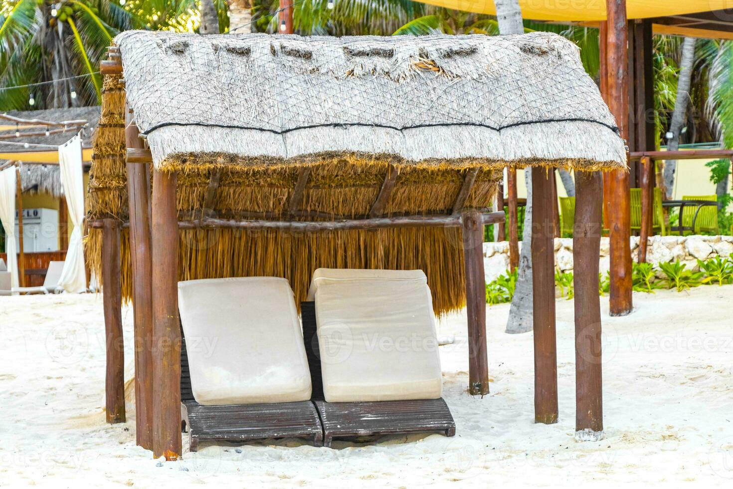 Palapa thatched roofs palms parasols sun loungers beach resort Mexico. photo