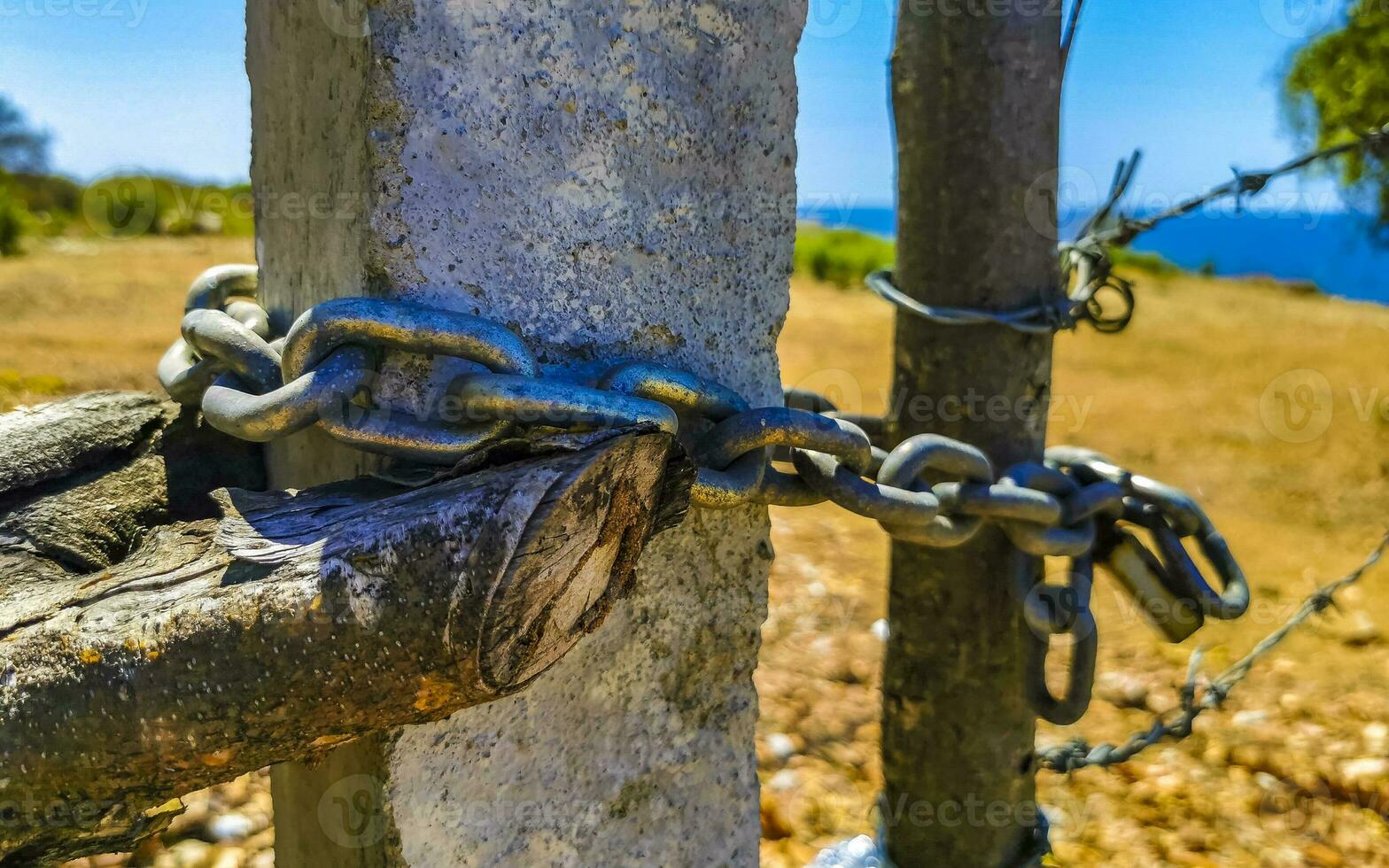 Nature beach and desert behind barbed wire fence and chains. photo