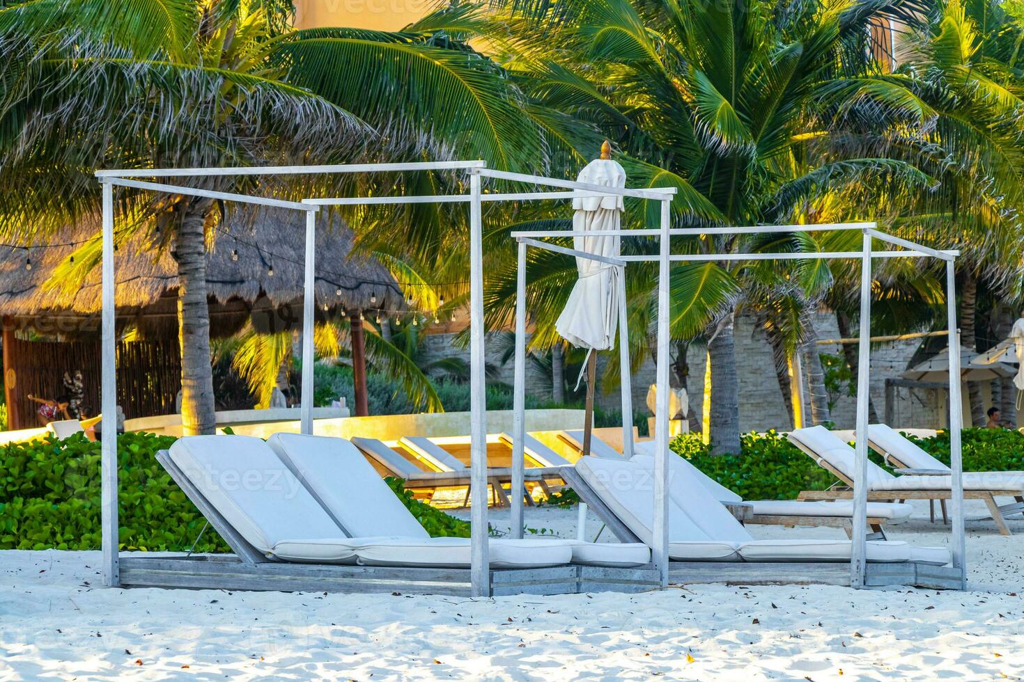 Palapa thatched roofs palms parasols sun loungers beach resort Mexico. photo