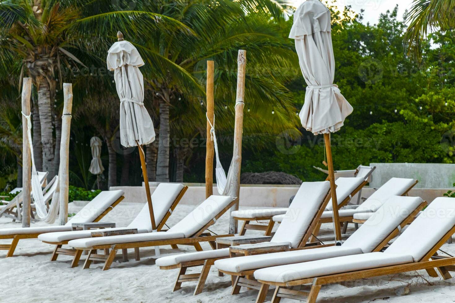 Palapa thatched roofs palms parasols sun loungers beach resort Mexico. photo