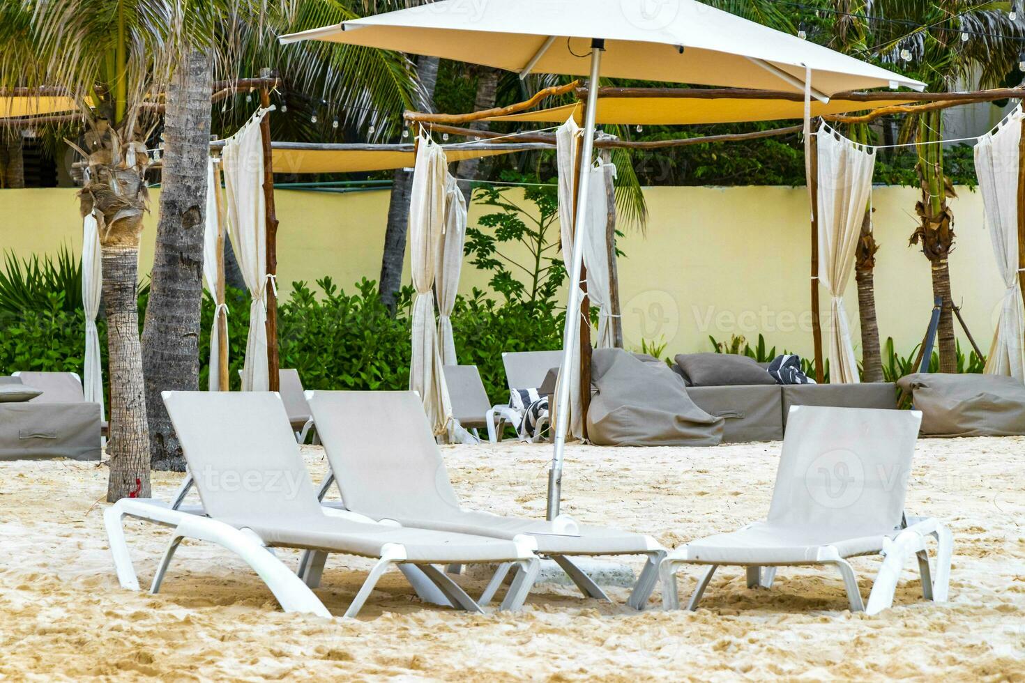 Palapa thatched roofs palms parasols sun loungers beach resort Mexico. photo
