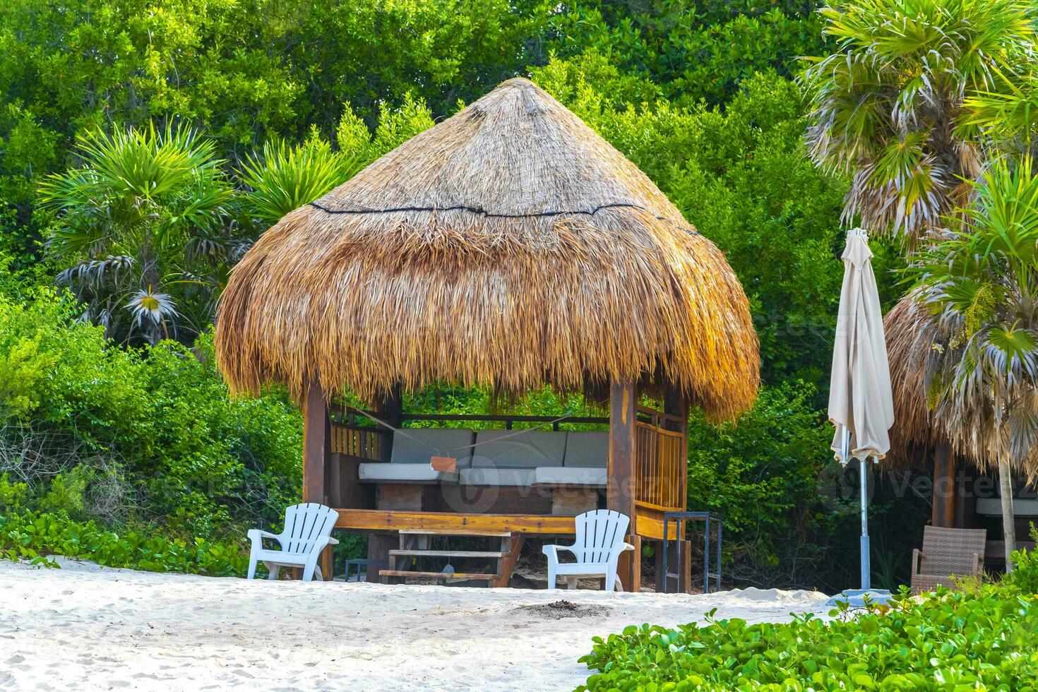 Palapa thatched roofs palms parasols sun loungers beach resort Mexico. photo