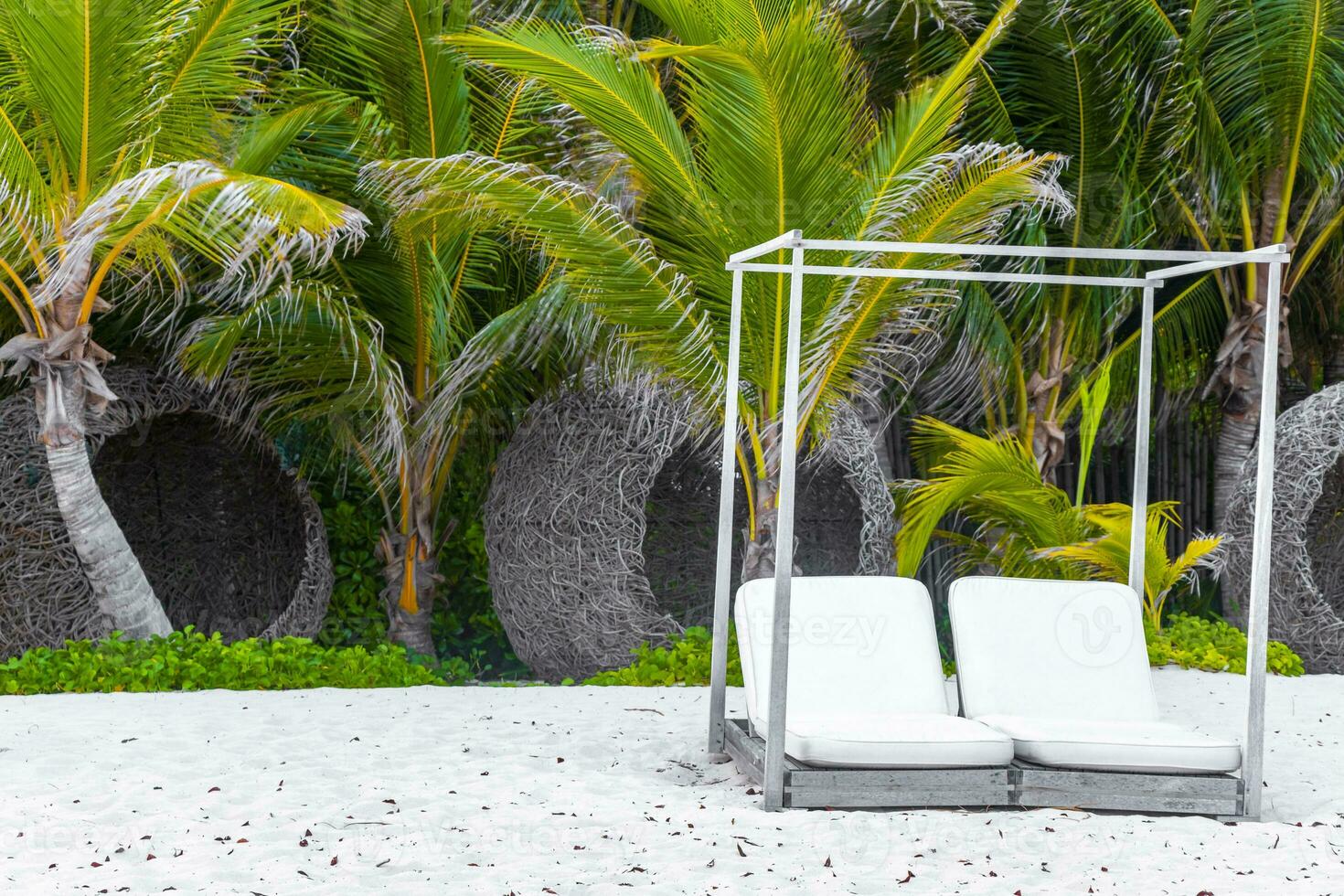 Palapa thatched roofs palms parasols sun loungers beach resort Mexico. photo