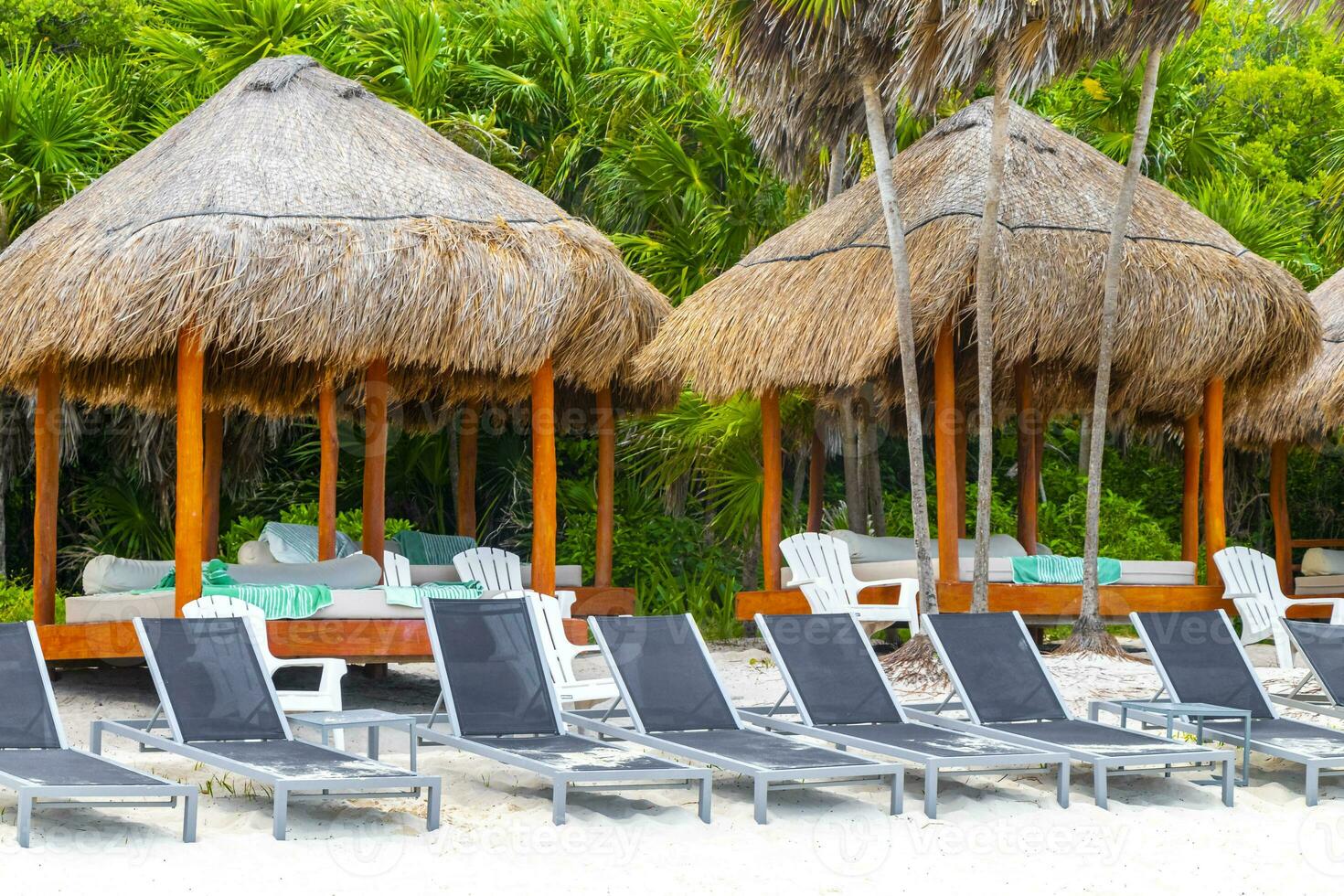 Palapa thatched roofs palms parasols sun loungers beach resort Mexico. photo