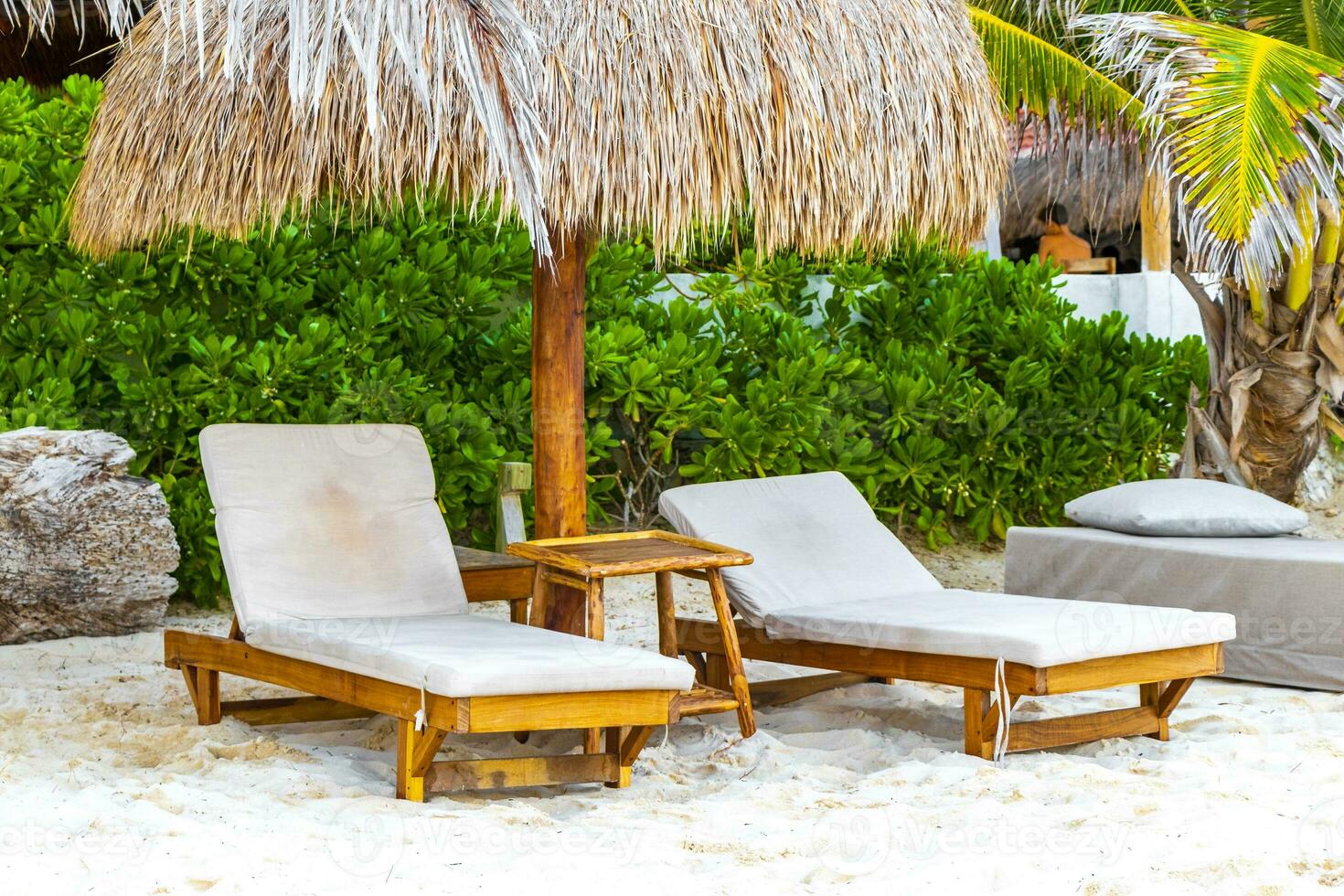Palapa thatched roofs palms parasols sun loungers beach resort Mexico. photo